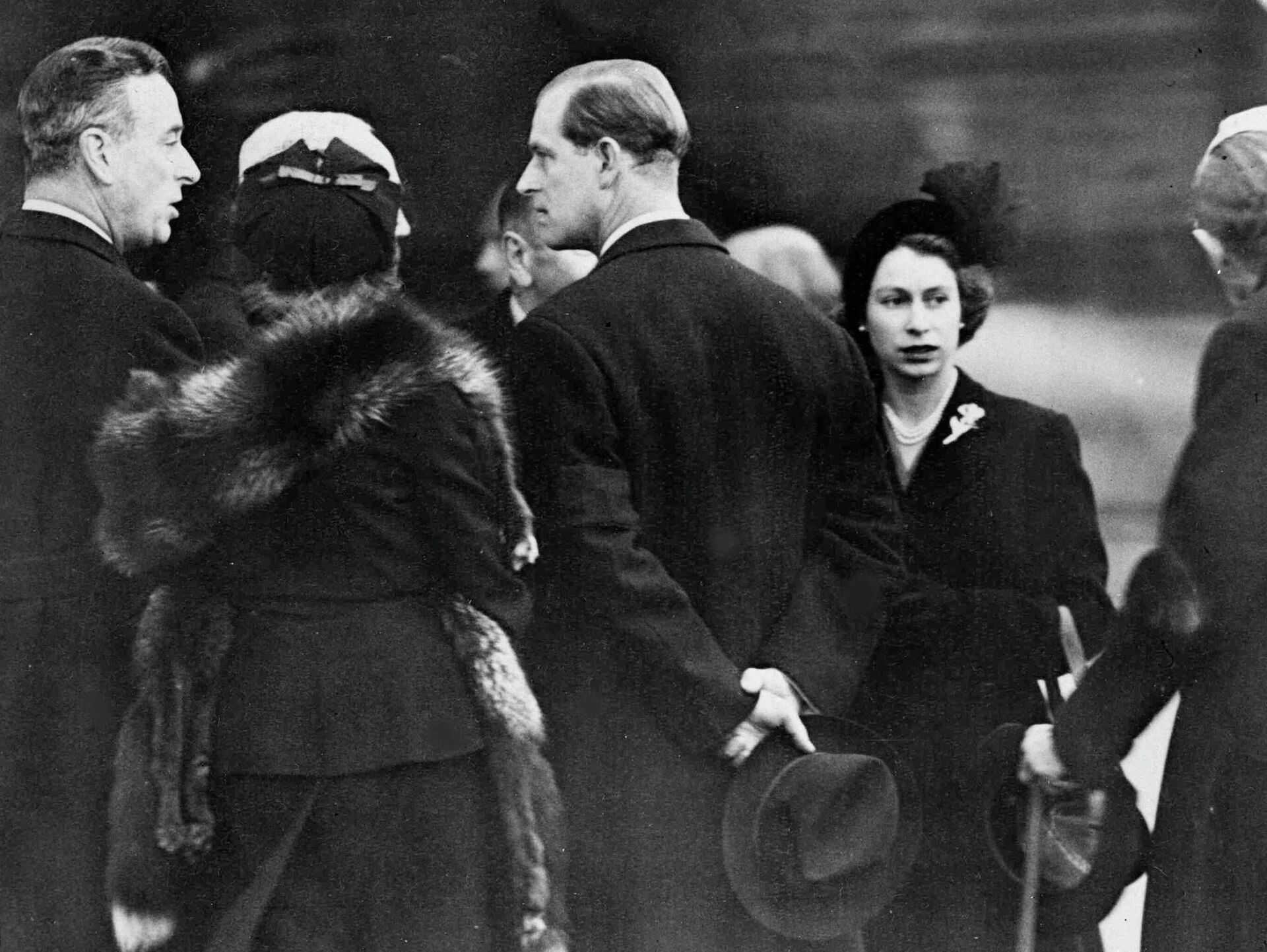 Britain's Queen Elizabeth II, right, and her husband Prince Philip, the Duke of Edinburgh, centre with back to camera, are greeted on their arrival at London Airport, on Feb. 7, 1952. The royal couple cut short their official trip to Kenya and returned home following the death of King George VI. Prince Philip is talking to Earl Louis Mountbatten of Burma, left. - Sputnik International, 1920, 10.09.2022