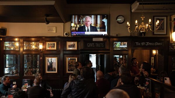 People watch a broadcast of Britain's King Charles III first address to the nation following the death of Queen Elizabeth II in London, Friday, Sept. 9, 2022. - Sputnik International