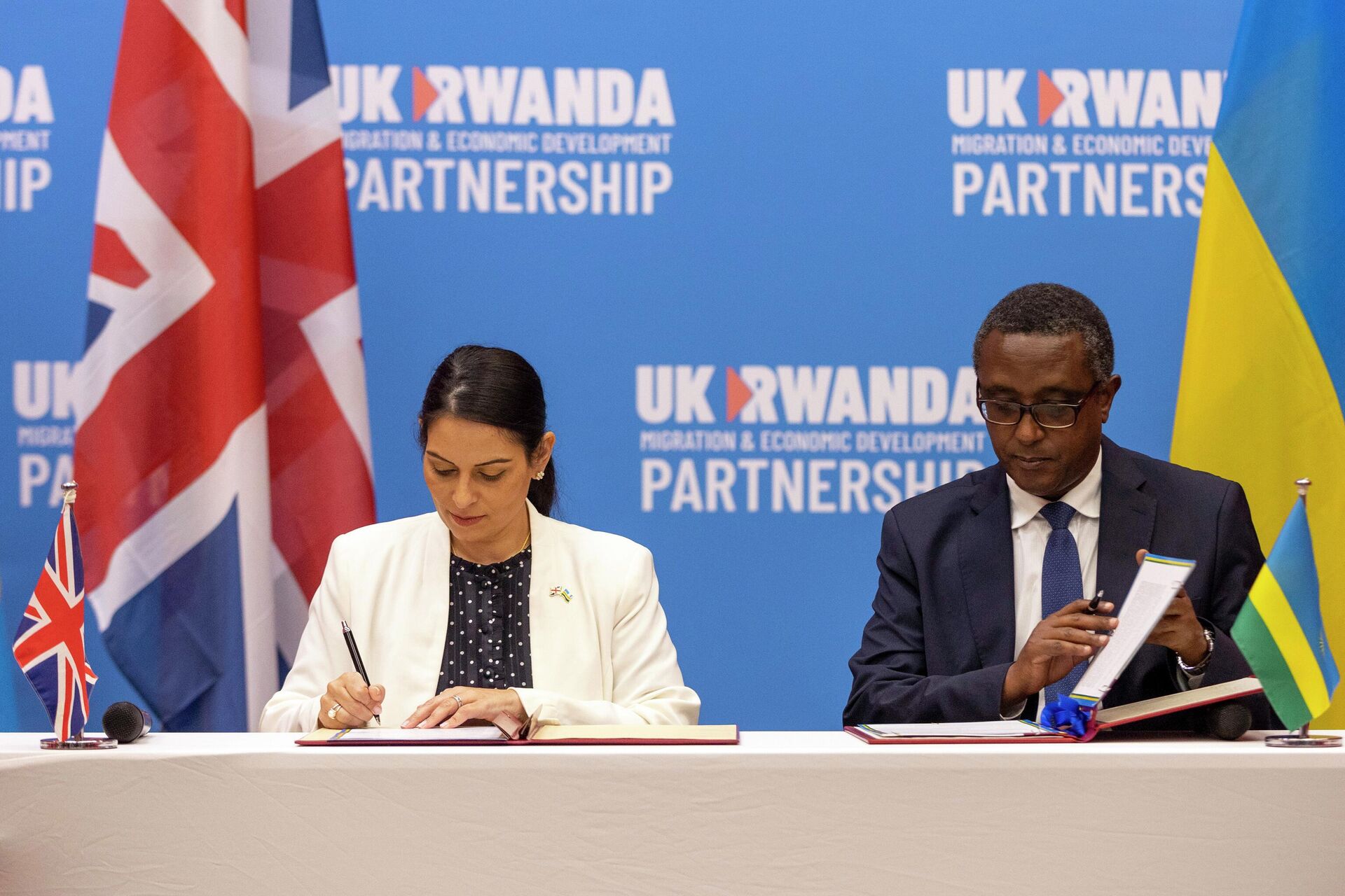 Britain's Home Secretary Priti Patel, left, and Rwanda's Minister of Foreign Affairs Vincent Biruta, right, sign what the two countries called an economic development partnership in Kigali, Rwanda Thursday, April 14, 2022. Britain's Conservative government has struck a deal to send some asylum-seekers thousands of miles away to Rwanda, a move that British opposition politicians and refugee groups condemned as inhumane, unworkable and a waste of public money. (AP Photo/Muhizi Olivier) - Sputnik International, 1920, 10.09.2022