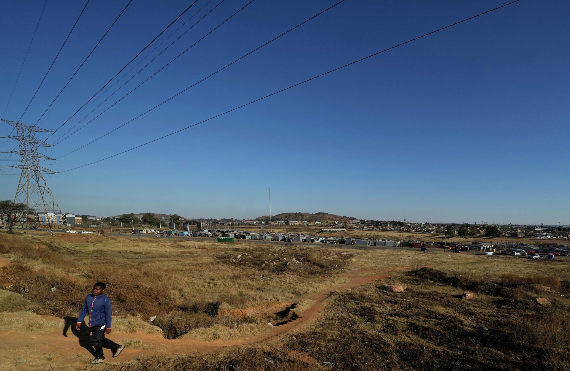 A man walks under the electricity power lines in Nomzamo Park, Soweto, Soweto, South Africa, Thursday, July 14, 2022. (AP Photo/Themba Hadebe) - Sputnik International, 1920, 11.09.2022