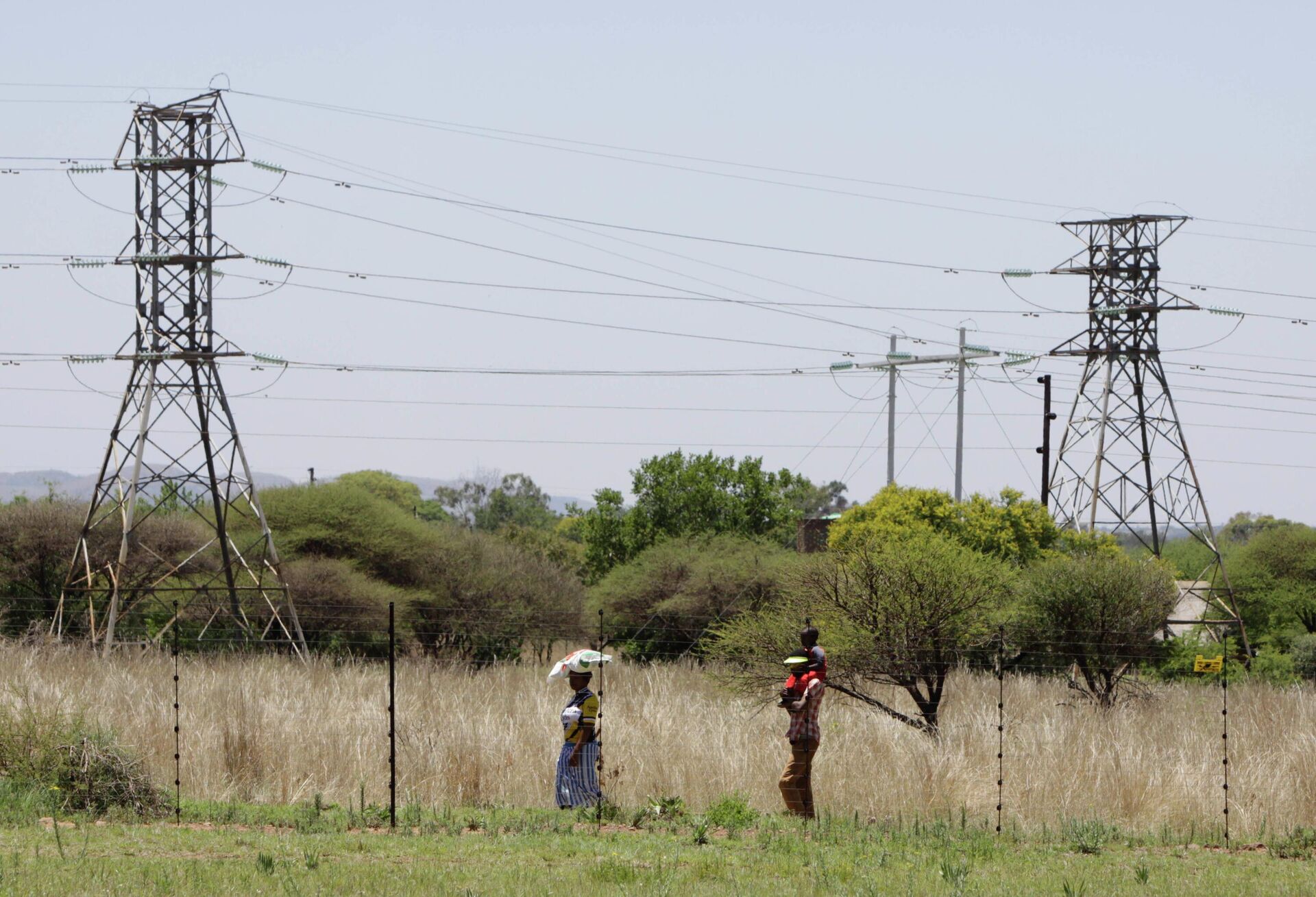 People walk below power pylons at Hartebeespoort, South Africa, Friday Nov. 25, 2011.  Eskom is Africa's biggest power utility, accounting for more than 60 percent of all the electricity generated on the continent, according to the World Bank. It also exports across southern Africa. Critics and even supporters say Eskom should have started its move toward renewable sources of energy earlier, and now needs to set its ambitions higher. (AP Photo/Denis Farrell) - Sputnik International, 1920, 23.12.2022