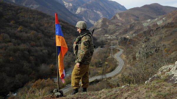 FILE - In this Wednesday, Nov. 25, 2020 file photo, An ethnic Armenian soldier stands guard next to Nagorno-Karabakh's flag atop of the hill near Charektar , Nov. 25, 2020 - Sputnik International