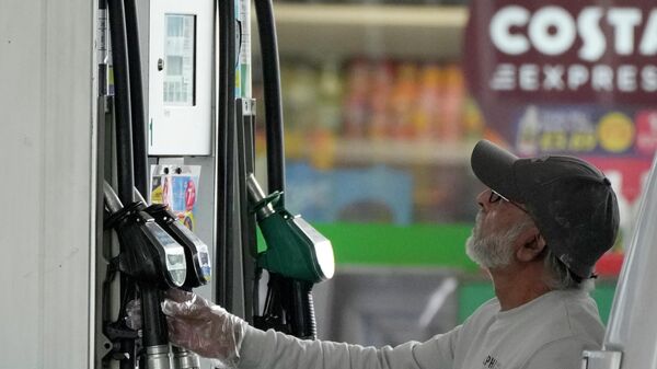 A driver looks at the petrol pump at a petrol station in London - Sputnik International