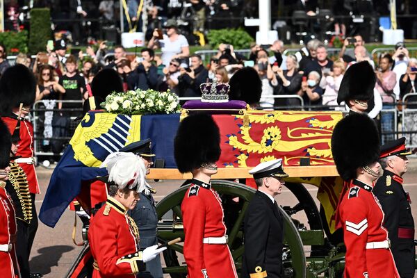 The coffin of Queen Elizabeth II, adorned with a Royal Standard and the Imperial State Crown and pulled by a Gun Carriage of The King&#x27;s Troop Royal Horse Artillery, is pictured during a procession from Buckingham Palace to the Palace of Westminster, in London on September 14, 2022. - Queen Elizabeth II will lie in state in Westminster Hall inside the Palace of Westminster, from Wednesday until a few hours before her funeral on Monday, with huge queues expected to file past her coffin to pay their respects. - Sputnik International