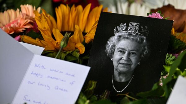 A portrait of late Queen Elizabeth II is pictured among flowers and tributes left in Green Park in London on September 18, 2022, following her death on September 8 - Sputnik International