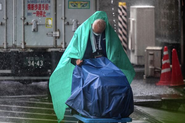 Сотрудник работает под проливным дождем, вызванным тайфуном Нанмадол, в токийском районе Уэно  - Sputnik International