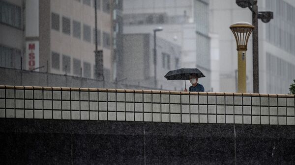 A man walks with an umbrella under heavy rain brought about by Typhoon Nanmadol, in Ueno district of Tokyo on September 18, 2022.  - Sputnik International