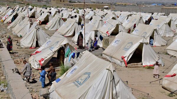 Victims of heavy flooding from monsoon rains stand beside their tents at a relief camp in Dasht near Quetta, Pakistan, Friday, Sept. 16, 2022. - Sputnik International