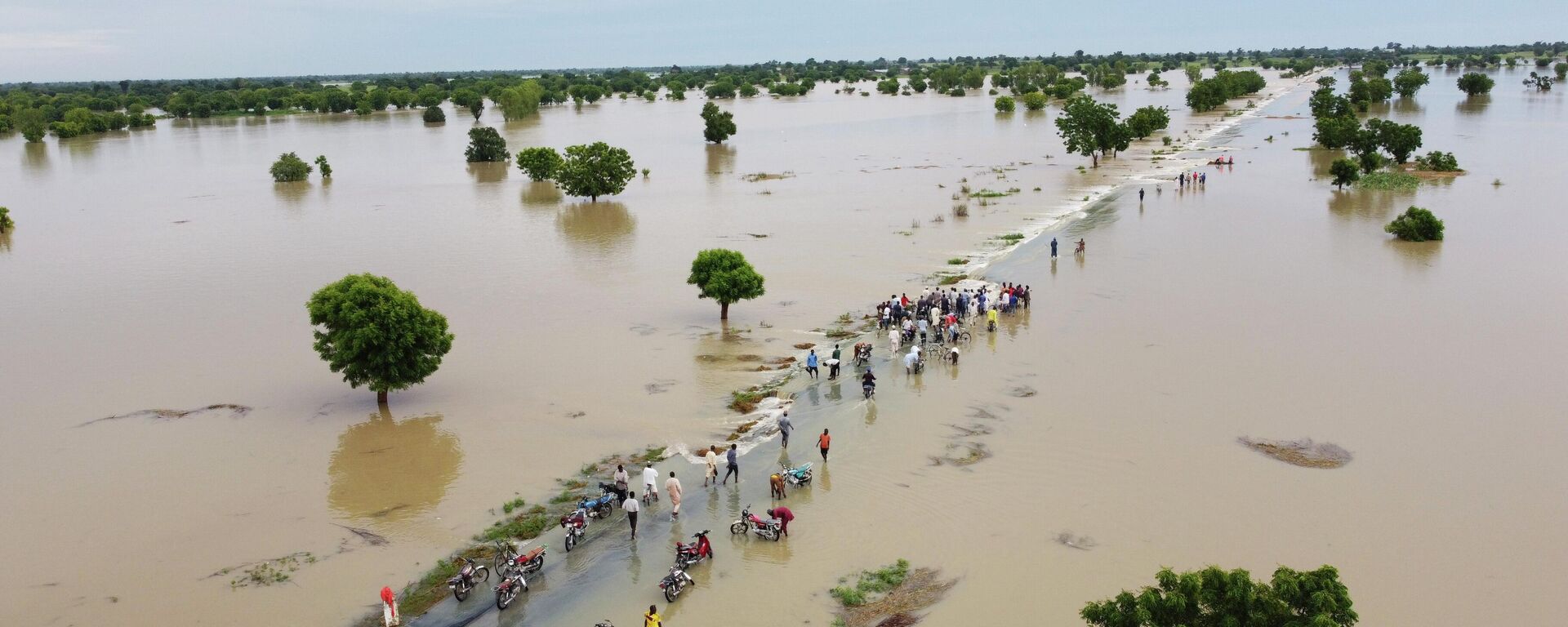 People walk through floodwaters after heavy rainfall in Hadeja, Nigeria, Monday, Sept 19, 2022. Nigeria is battling its worst floods in a decade with more than 300 people killed in 2021 including at least 20 this week, authorities told the Associated Press on Monday. - Sputnik International, 1920, 20.09.2022
