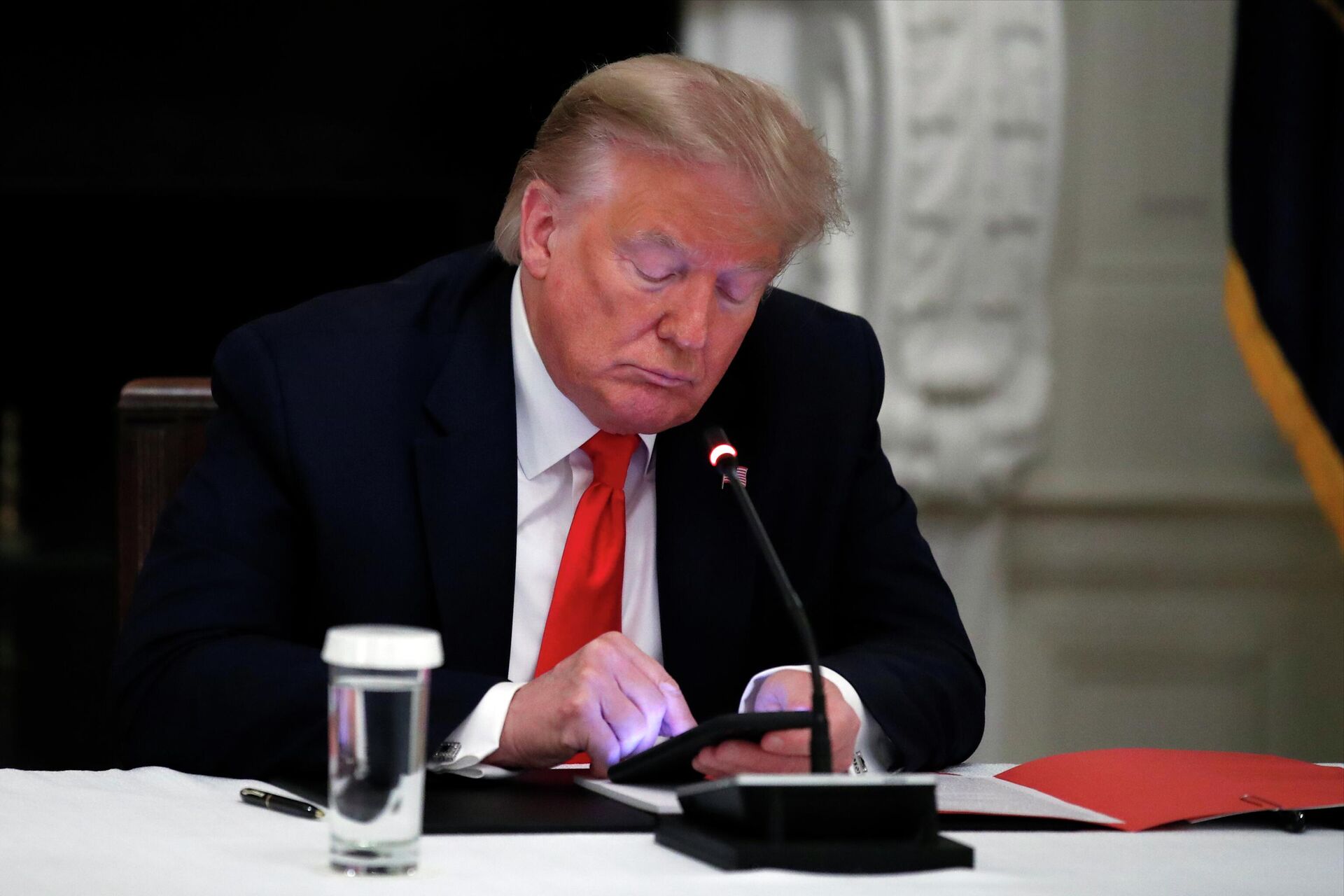 President Donald Trump looks at his phone during a roundtable with governors on the reopening of America's small businesses, in the State Dining Room of the White House in Washington, June 18, 2020 - Sputnik International, 1920, 15.11.2022