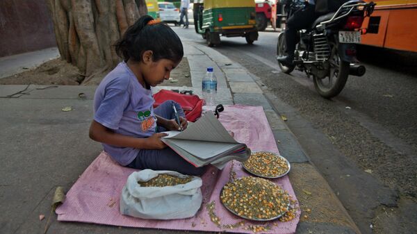Indian girl Pratigya, studies while she sells a mix of corn and millets that commuters buy to feed pigeons on a busy pavement in central New Delhi, India, Wednesday, March 28, 2018. - Sputnik International