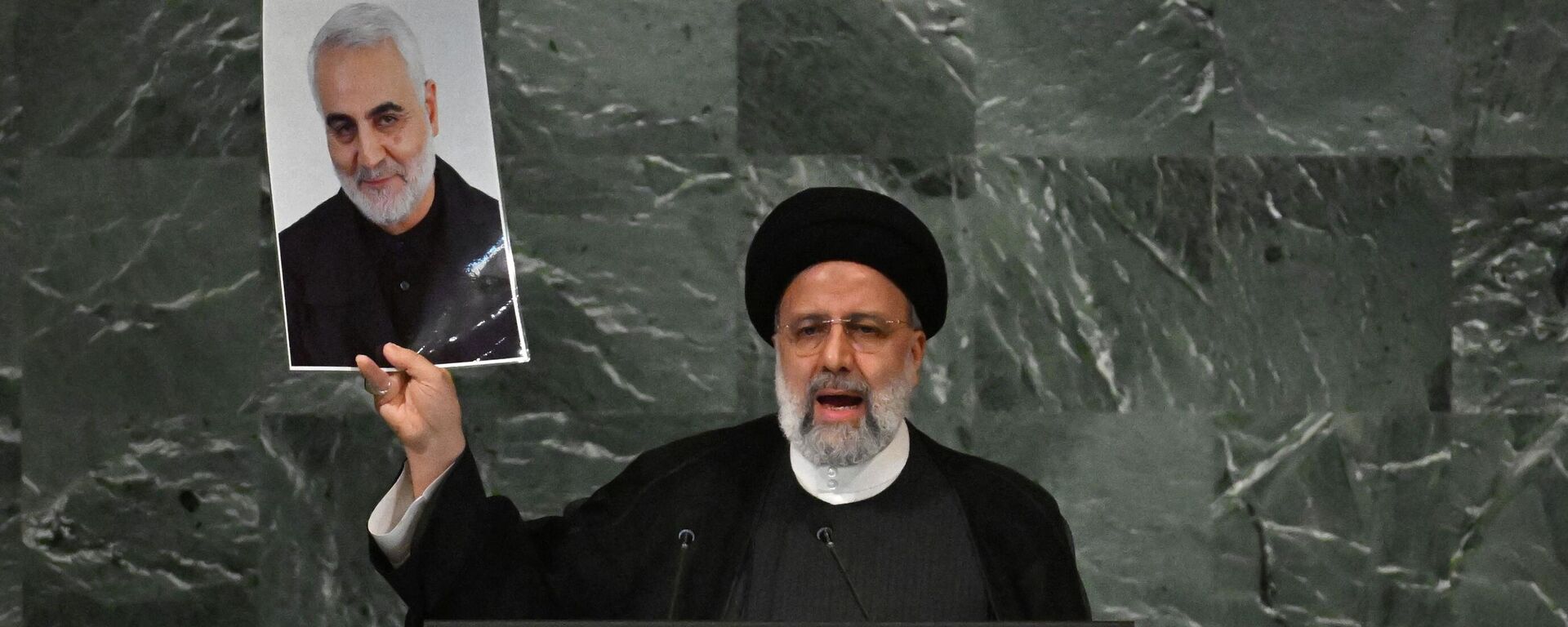 Iranian President Ebrahim Raisi addresses the 77th session of the United Nations General Assembly at the UN headquarters in New York City on September 21, 2022, while holding a photo of Iranian General Qasem Soleimani killed by a US drone strike in Baghdad in January 2020. - Sputnik International, 1920, 21.09.2022