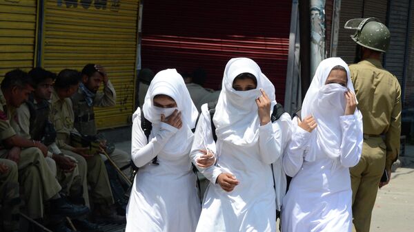 Kashmiri schoolgirls walk past Indian policemen as they conduct a patrol in Srinagar - Sputnik International