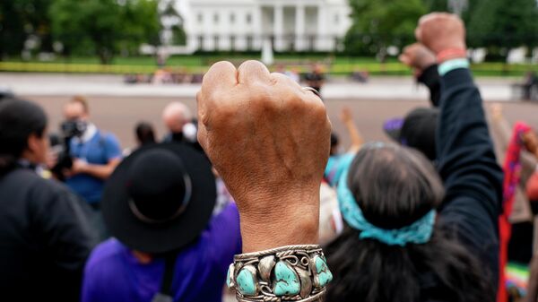 Wolf Ramerez of Houston, Texas, center, joins others with the Carrizo Comecrudo Tribe of Texas in holding up his fists as indigenous and environmental activists protest in front of the White House in Washington, Oct. 11, 2021. - Sputnik International