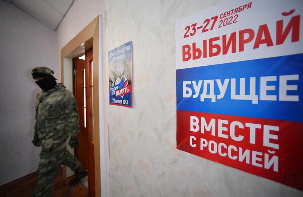 A member of a volunteer detachment at a polling station in Melitopol during the referendum on the  accession of the Zaporozhye region to Russia. - Sputnik International