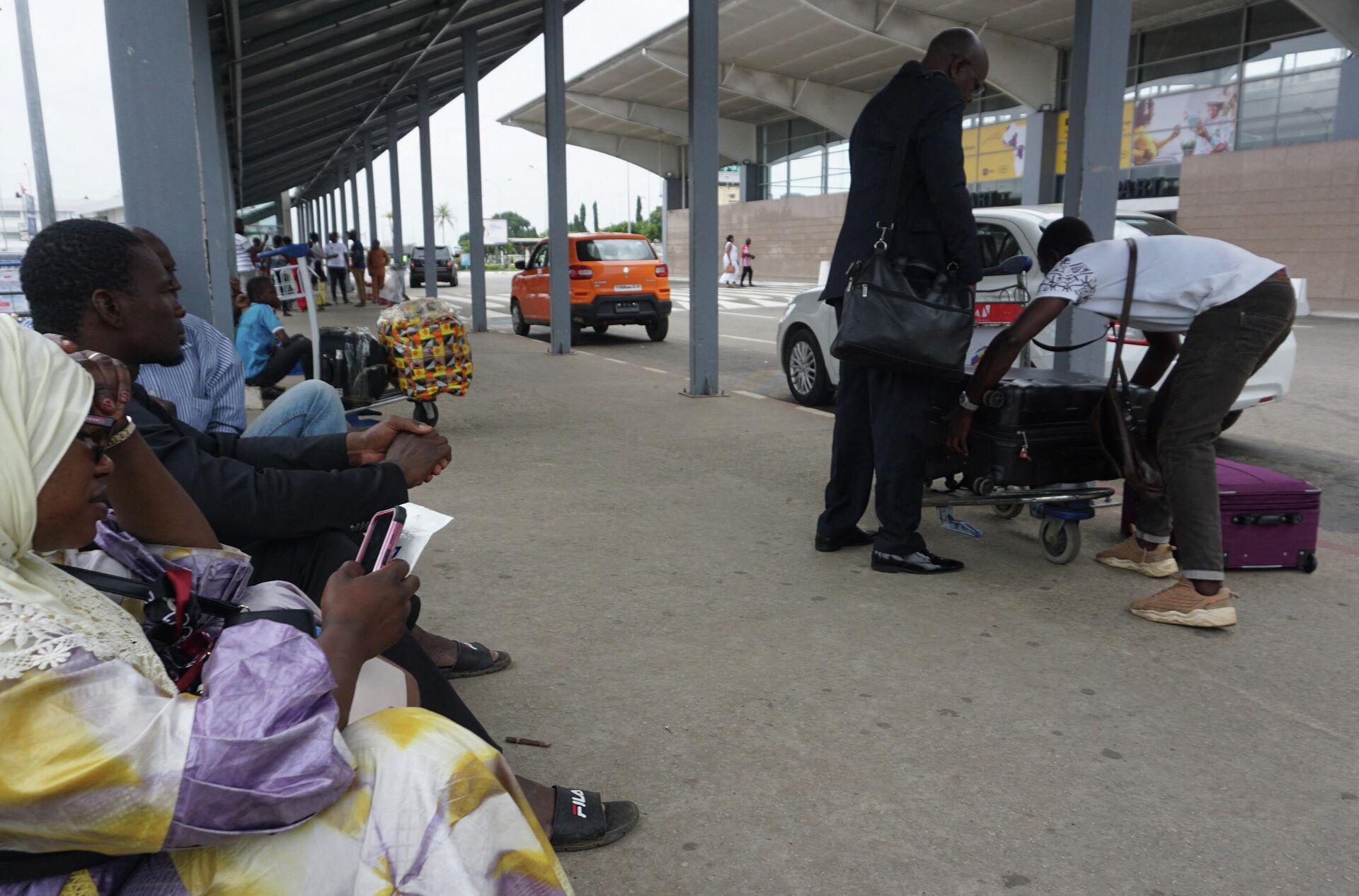 People wait by their luggage outside the Felix Houphouet Boigny International airport in Abidjan on September 24, 2022,  after a strike by air traffic controllers, that started Friday,  paralysed serval West African airports with all commercial flights cancelled. (Photo by Issouf SANOGO / AFP) - Sputnik International, 1920, 25.09.2022