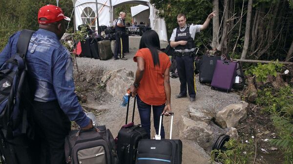FILE - In this Aug. 7, 2017, file photo, a Royal Canadian Mounted Police officer informs a migrant couple of the location of a legal border station, shortly before they illegally crossed from Champlain, N.Y., to Saint-Bernard-de-Lacolle, Quebec, using Roxham Road - Sputnik International