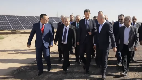 Syrian President Bashar Assad touring a new solar power plant facility established thanks to a public-private partnership. Screengrab of video. - Sputnik International