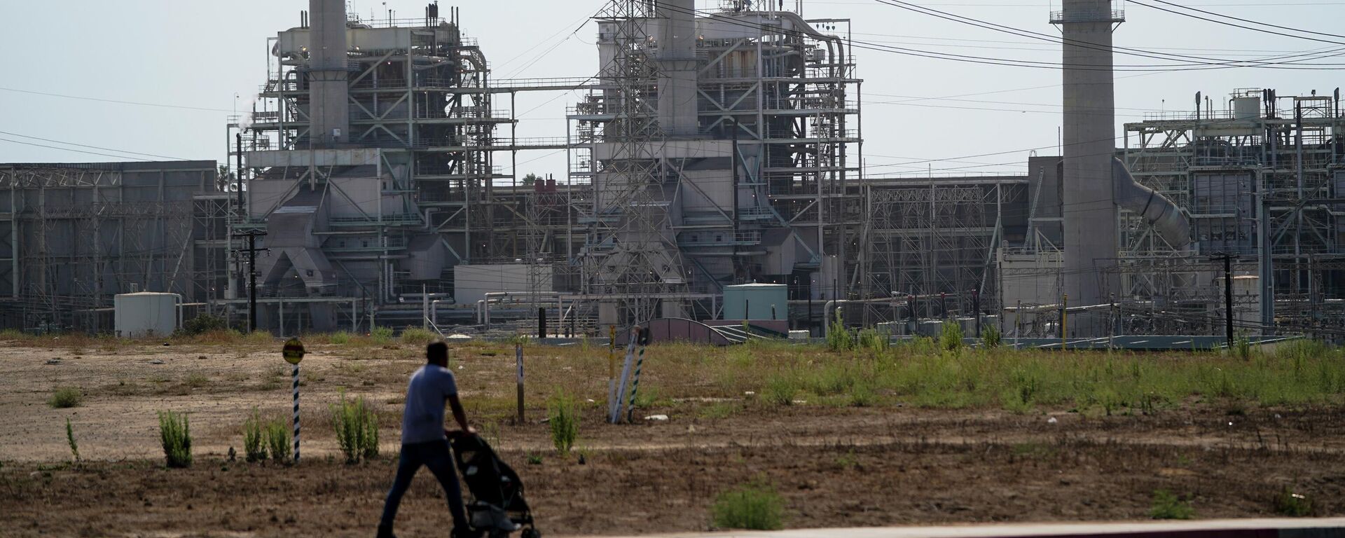 FILE - A man pushes a stroller near the AES power plant in Redondo Beach, Calif., Wednesday, Sept. 7, 2022.  On Monday, Sept. 19, the world’s first public database of fossil fuel production, reserves and emissions launches.  It shows that the United States and Russia have enough fossil fuel reserves to exhaust the world’s remaining carbon budget to stay under 1.5 degrees Celsius warming. (AP Photo/Jae C. Hong, File) - Sputnik International, 1920, 05.10.2022