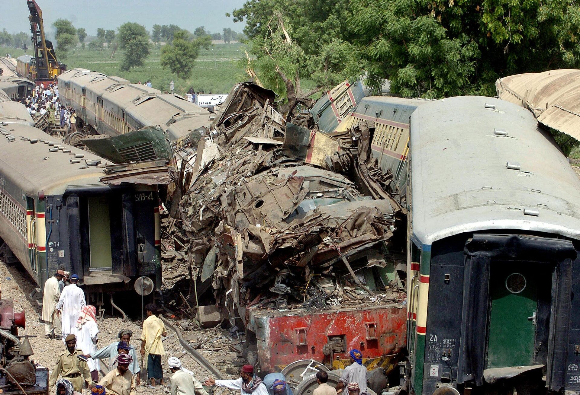 Pakistani villagers gather around the wreckage of three trains following a crash in Ghotki, 13 July 2005. Three crowded passenger trains collided in a devastating crash at a station in southern Pakistan, killing up to 150 people, injuring 1,000 and leaving many others trapped, officials said. Rescuers were trying to extract hundreds of people still trapped in the mangled carriages of the three trains, which lay scattered amid piles of debris and body parts, and police warned the death toll would likely rise.  - Sputnik International, 1920, 07.10.2022