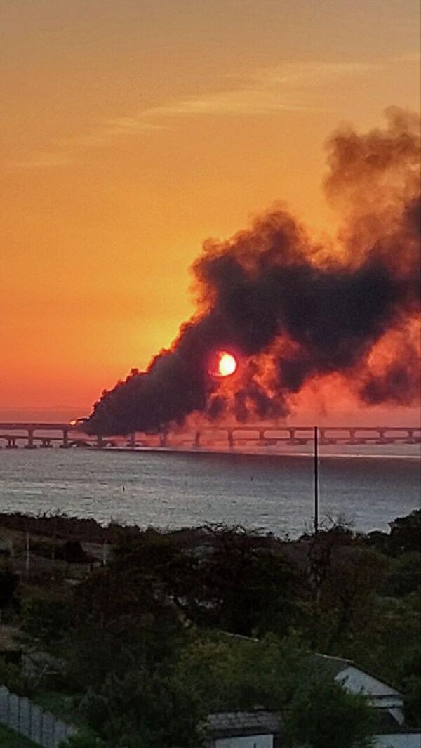 Billowing black smoke seen rising from the Crimean Bridge, after the explosion of a truck which caused the seven fuel tanks of a train to catch fire. - Sputnik International