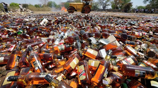 A road roller is used to destroy seized liquor bottles as police officials oversee in Ahmedabad, Gujarat state, India, Wednesday, March 30, 2022. - Sputnik International