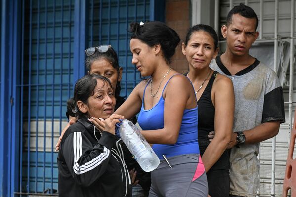 Residents comfort each other as rescuers search for their missing relatives in the rubble of a house destroyed by a landslide during heavy rains in Las Tejerias, Aragua state, Venezuela, on October 9, 2022. - Sputnik International
