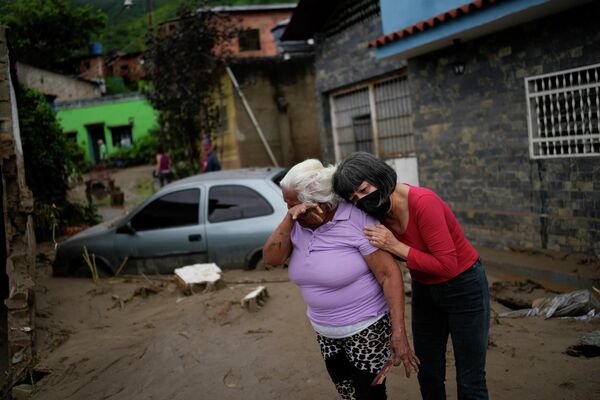 Women embrace in a flooded street outside their home in Las Tejerias, Venezuela, Sunday, Oct. 9, 2022. - Sputnik International