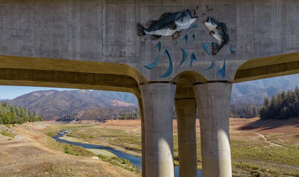 A mural depicting jumping fish adorns a bridge that spans a mostly dry section of Lake Shasta in Lakehead, California, Oct. 16, 2022. - Shasta Lake currently sits at 32% of its capacity as drought conditions persist throughout the west. - Sputnik International