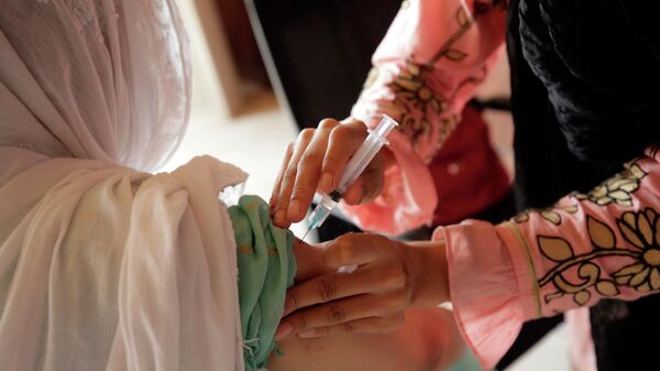 A woman receives the Sinopharm COVID-19 vaccine from a health worker at a vaccination center in Islamabad, Pakistan, Monday, Oct. 4, 2021. - Sputnik International
