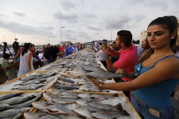Женщина держит рыбу в день, когда члены Ливанской ассоциации торговцев побили мировой рекорд Гиннесса по самой большой выставке морепродуктов  - Sputnik International