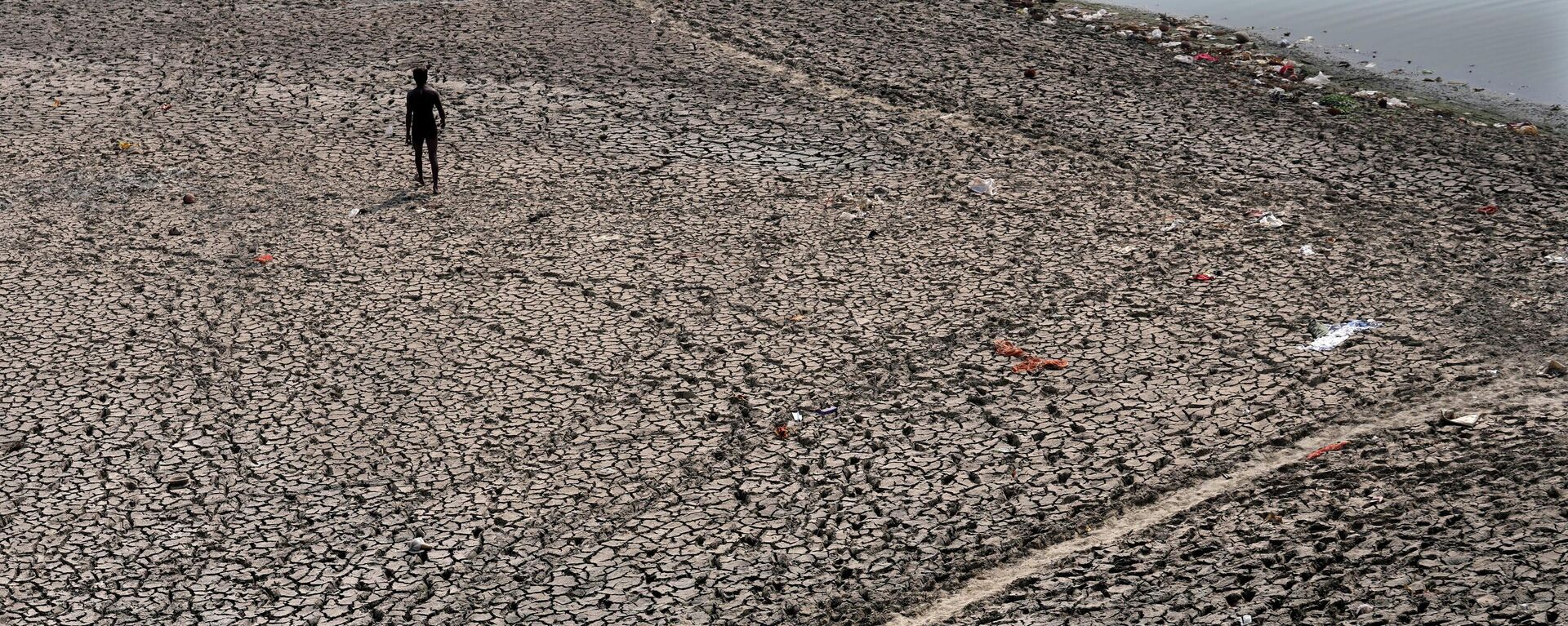 A man walks across a dried bed of river Yamuna where water levels have reduced drastically following hot weather in New Delhi, India, Monday, May 2, 2022. - Sputnik International, 1920, 21.10.2022