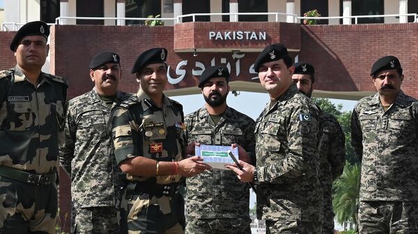 Indian Border Security Force (BSF) commandant Jasbir Singh (3L) receives sweets from Pakistan's Rangers wing commander Aamir (3R) on the occasion of the Hindu festival of Diwali at the India-Pakistan Wagah border post, about 35km from Amritsar on October 24, 2022. - Sputnik International
