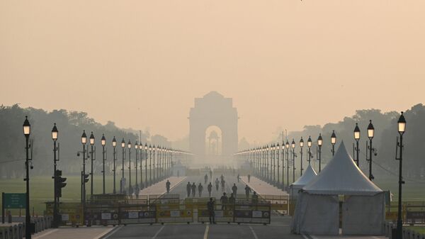 People walk along a road near India Gate amid smoggy conditions in New Delhi on October 25, 2022. - Sputnik International