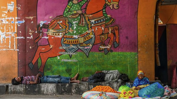 A woman sells flowers as homeless men naps under a flyover on a hot summer day in New Delhi on July 2, 2021. - Sputnik International