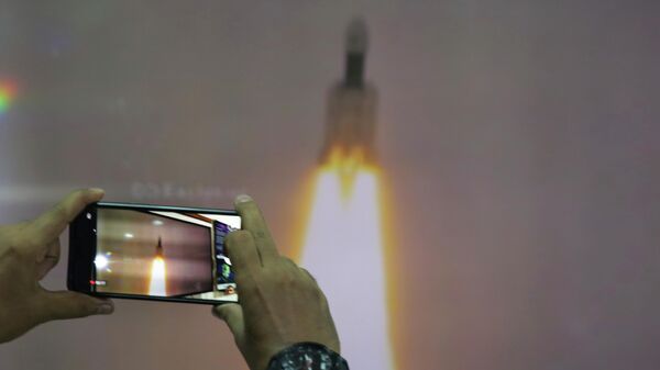 A man at New Delhi's Nehru Planetarium, takes pictures of a web cast of the lift off of Indian Space Research Organization (ISRO)'s Geosynchronous Satellite launch Vehicle (GSLV) MkIII carrying Chandrayaan-2 from Satish Dhawan Space center in Sriharikota, India, Monday, July 22, 2019. - Sputnik International