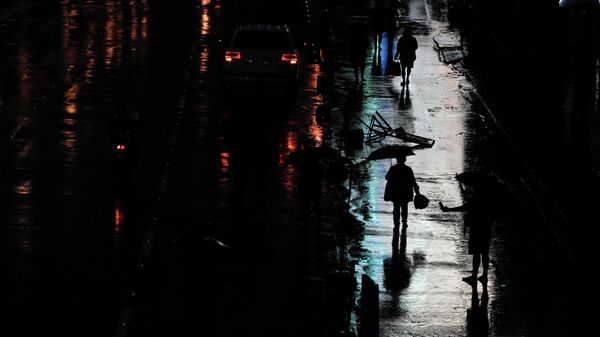 A woman walks under the rain caused by Tropical Storm Nalgae as she waits for a ride in Manila, Philippines on Saturday Oct. 29, 2022. Flash floods and landslides set off by torrential rains left at least 50 people dead, including in a hard-hit southern Philippine province, where as many as 60 villagers are feared missing and buried in a huge mudslide laden with rocks, trees and debris, officials said Saturday. - Sputnik International