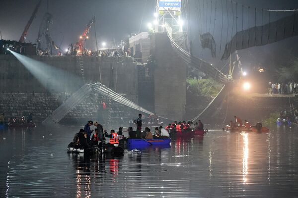 Indian rescue personnel conduct search operations after a bridge across the river Machchhu collapsed in Morbi, some 220 km from Ahmedabad, early on October 31, 2022. - At least 75 people were killed on October 30 in India after an almost 150-year-old colonial-era pedestrian bridge collapsed, sending scores of people tumbling into the river below. (Photo by SAM PANTHAKY / AFP) - Sputnik International