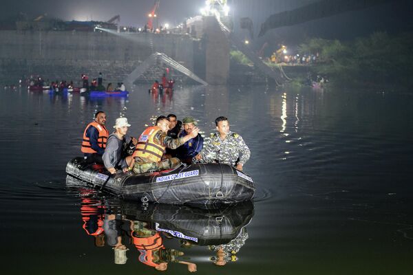 Indian rescue personnel conduct search operations after a bridge across the Machchhu River collapsed in Morbi, some 220 km from Ahmedabad, early on October 31, 2022. At least 75 people were killed on October 30 in India after an almost 150-year-old colonial-era pedestrian bridge collapsed, sending scores of people tumbling into the river below. - Sputnik International