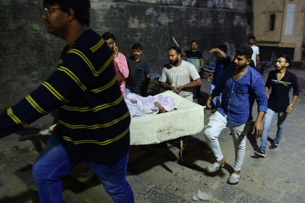 Volunteers carry a recovered body to a waiting ambulance as Indian rescue personnel conduct search operations after a bridge across the Machchhu River collapsed in Morbi, some 220 km from Ahmedabad, early on October 31, 2022. At least 120 people were killed in India after a colonial-era pedestrian bridge collapsed, sending scores of people tumbling into the river below, police said on October 31. - Sputnik International