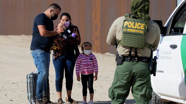 A young migrant from Cuba looks on as her parents prepare documents to show the border patrol agent after they crossed the US-Mexico border and turned themselves to authorities on May 13, 2021 in Yuma, Arizona - Sputnik International