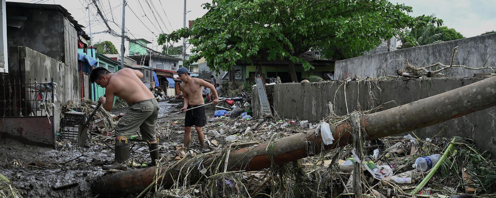 Men clean the debris along a debris-covered street in Noveleta, Cavite province on October 30, 2022, a day after Tropical Storm Nalgae hit. - - Sputnik International, 1920, 01.11.2022