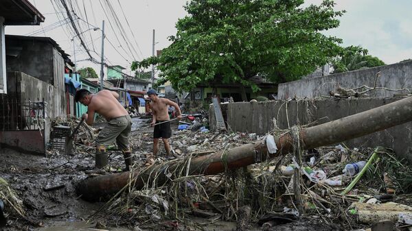 Men clean the debris along a debris-covered street in Noveleta, Cavite province on October 30, 2022, a day after Tropical Storm Nalgae hit. - - Sputnik International