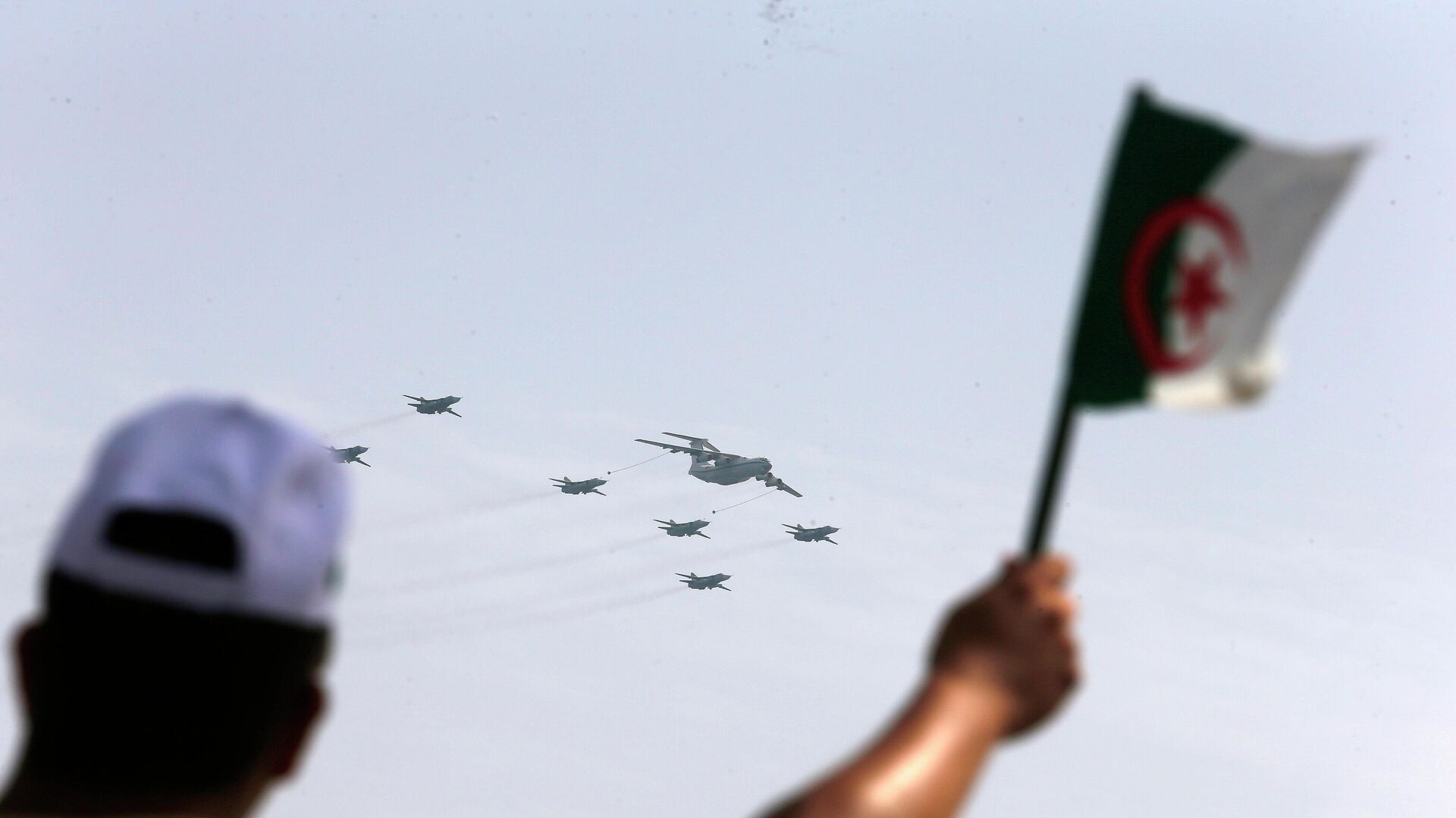 A man waves an Algerian flag as war planes fly during a military parade to mark the 60th anniversary of Algeria's independence, Tuesday, July 5, 2022 in Algiers.  - Sputnik International, 1920, 23.12.2022
