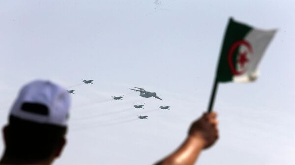 A man waves an Algerian flag as war planes fly during a military parade to mark the 60th anniversary of Algeria's independence, Tuesday, July 5, 2022 in Algiers.  - Sputnik International