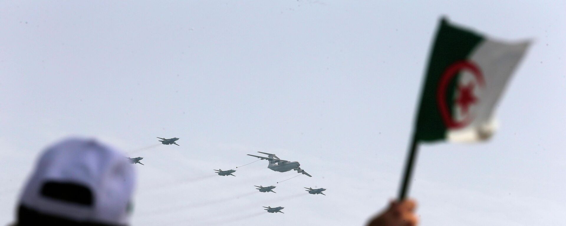 A man waves an Algerian flag as war planes fly during a military parade to mark the 60th anniversary of Algeria's independence, Tuesday, July 5, 2022 in Algiers.  - Sputnik International, 1920, 27.02.2023