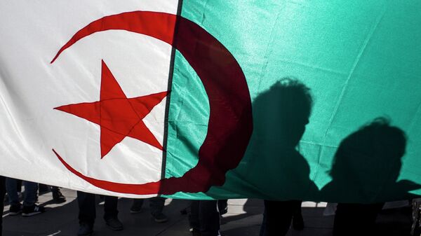 Demonstrators are silhouetted against a national Algerian flag as they stage a protest on the Republique Plaza to press for an end to the 20-year-rule of Algerian President Abdelaziz Bouteflika, in Paris, France, Sunday, March 17, 2019.  - Sputnik International