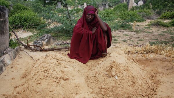 Fatuma Abdi Aliyow sits by the graves of her two sons who died of malnutrition-related diseases last week, at a camp for the displaced on the outskirts of Mogadishu, Somalia, Sept. 3, 2022. - Sputnik International