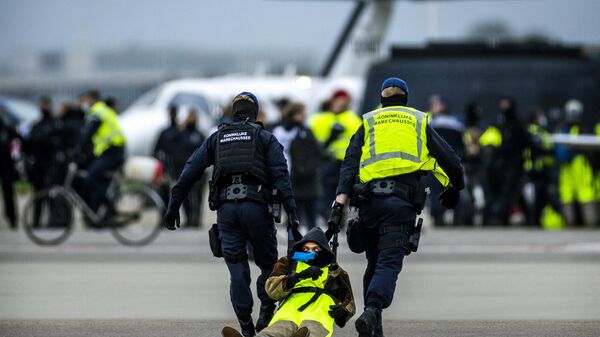 The Marechaussee arrest a protester as Milieudefensie, Extinction Rebellion, Greenpeace and other organisations members sit in front of an aircraft during a protest 'SOS for the climate' at Schiphol Airport, near Amsterdam on November 5, 2022. - Sputnik International