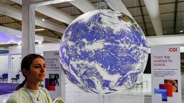 A participant walks past a mockup of the planet Earth globe at the Sharm el-Sheikh International Convention Centre, on the first day of the COP27 climate summit, in Egypt's Red Sea resort city of Sharm el-Sheikh, on November 6, 2022. - Sputnik International